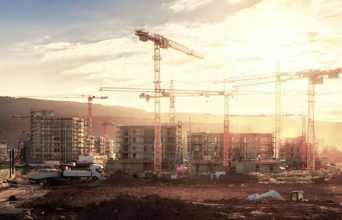 Baustelle eines Bürokomplexes mit mehreren Kränen bei Abendstimmung
