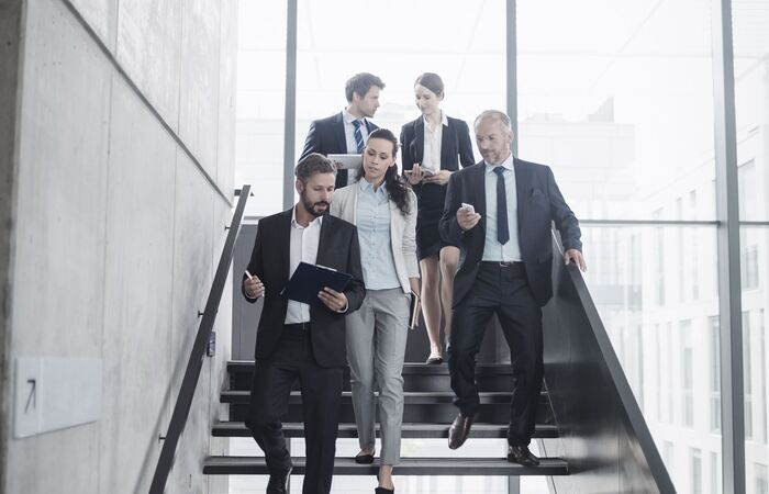 Gruppe von Geschäftsleuten, die im Gespräch gemeinsam eine Treppe herunter laufen