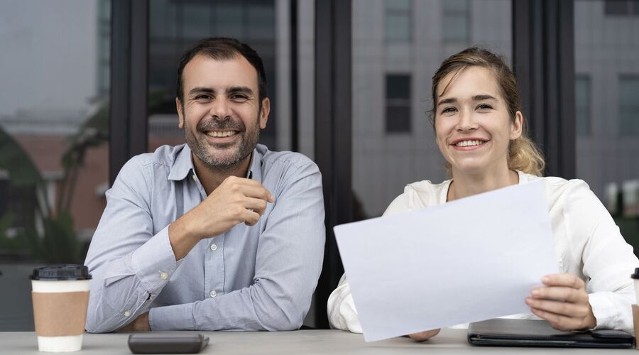 ein Mann und eine Frau sitzen am Tisch und lächeln in die Kamera