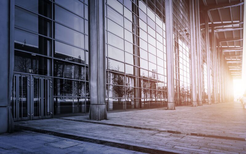 Abendstimmung vor einem großen Bürogebäude mit hoher, verglaster Front