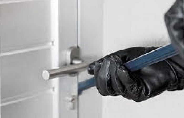 Einbrecher mit Einbruchswerkzeug in der Hand versucht eine Tür zu öffnen