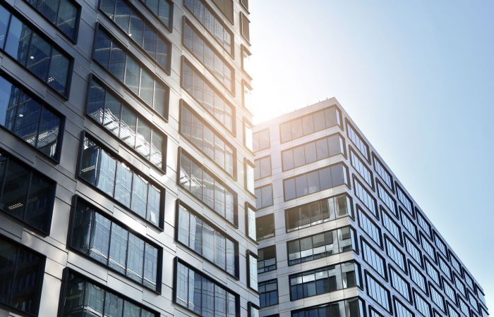 Ausschnitt einer Fassade eines modernen, verglasten Bürogebäudes mit Sonnenschein