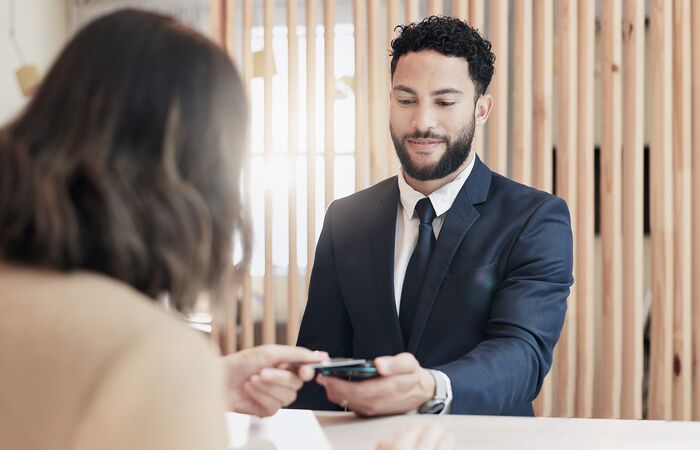 freundlicher Empfangsmitarbeiter scannt die Karte einer Besucherin ein