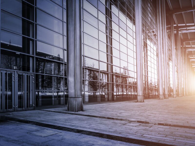Abendstimmung vor einem großen Bürogebäude mit hoher, verglaster Front
