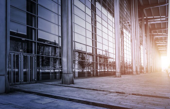 Abendstimmung vor einem großen Bürogebäude mit hoher, verglaster Front