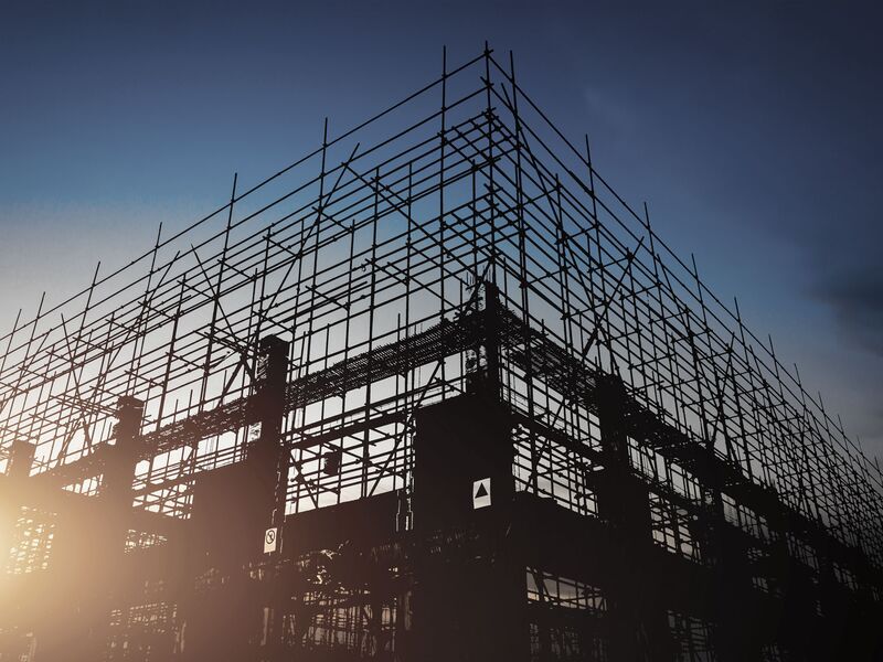 Baustelle bei Abendstimmung, bei der man die Armiereisen in den Himmel ragen sieht