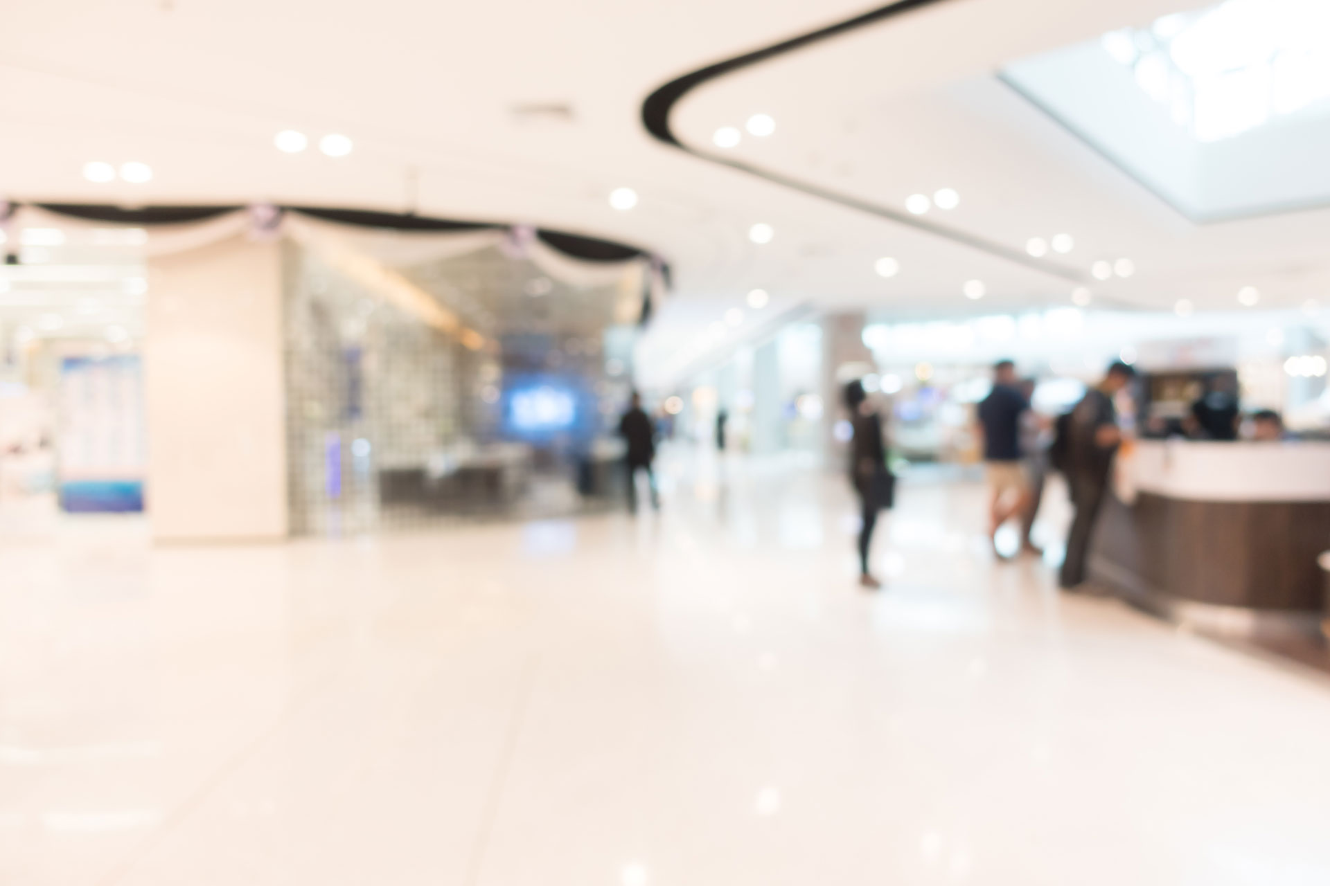 unscharfe Ansicht einer Eingangshalle eines Unternehmens, angenehm hell beleuchtet, Menschen stehen am Empfang