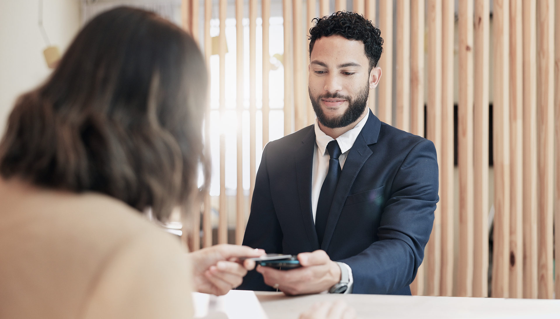 freundlicher Empfangsmitarbeiter scannt die Karte einer Besucherin ein